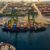 Shipping containers are loaded onto a large ship that is docked - used for wholesale suppliers.