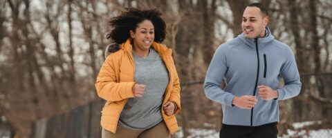 A Man and a woman Running on the road wearing a jacket